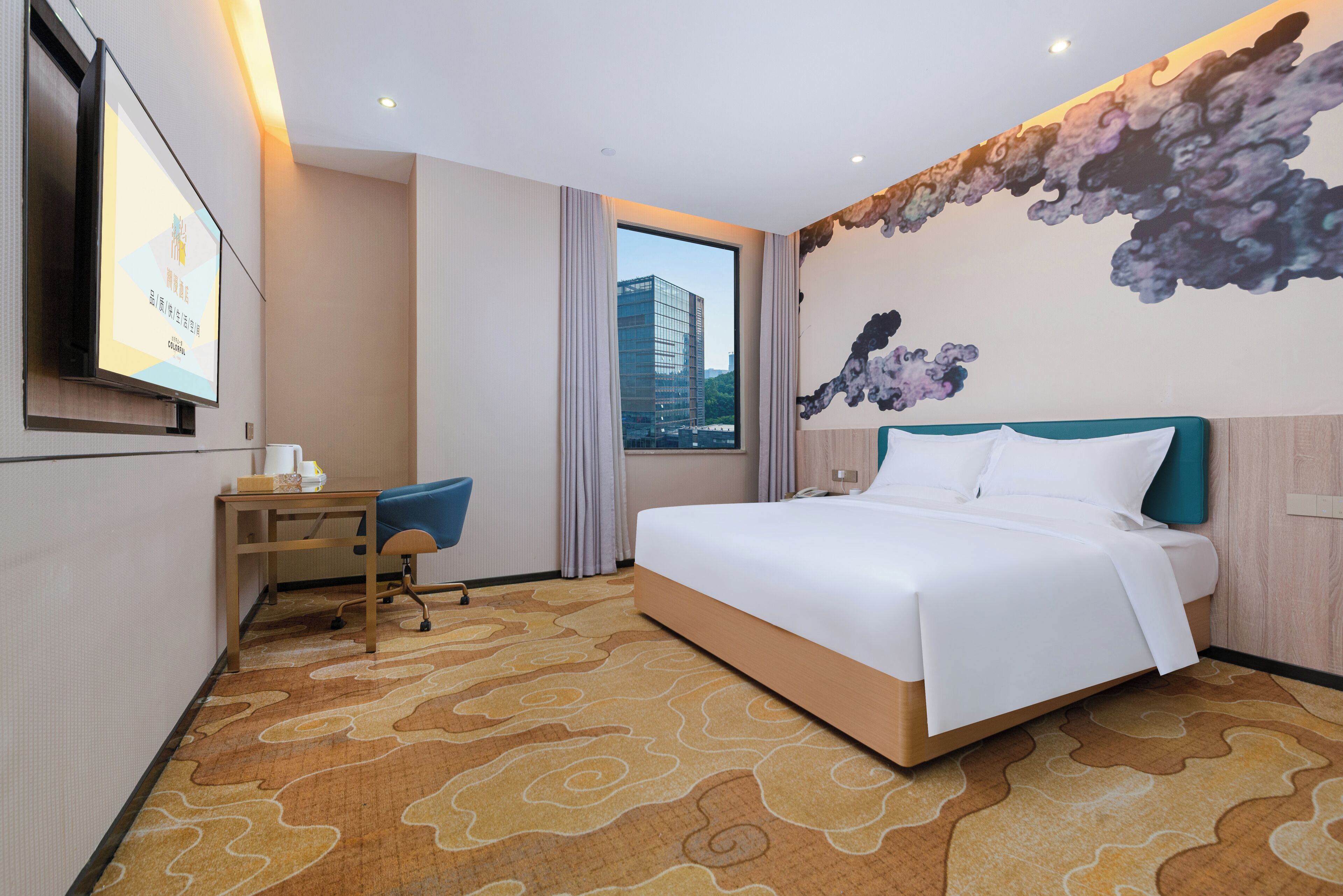 Hotelkamer met een groot bed, bureau met stoel, televisie aan de muur en uitzicht op een gebouw.
