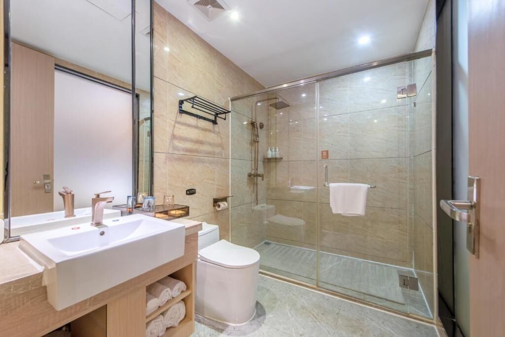 A modern bathroom with a large sink, toilet, and glass-enclosed shower.
