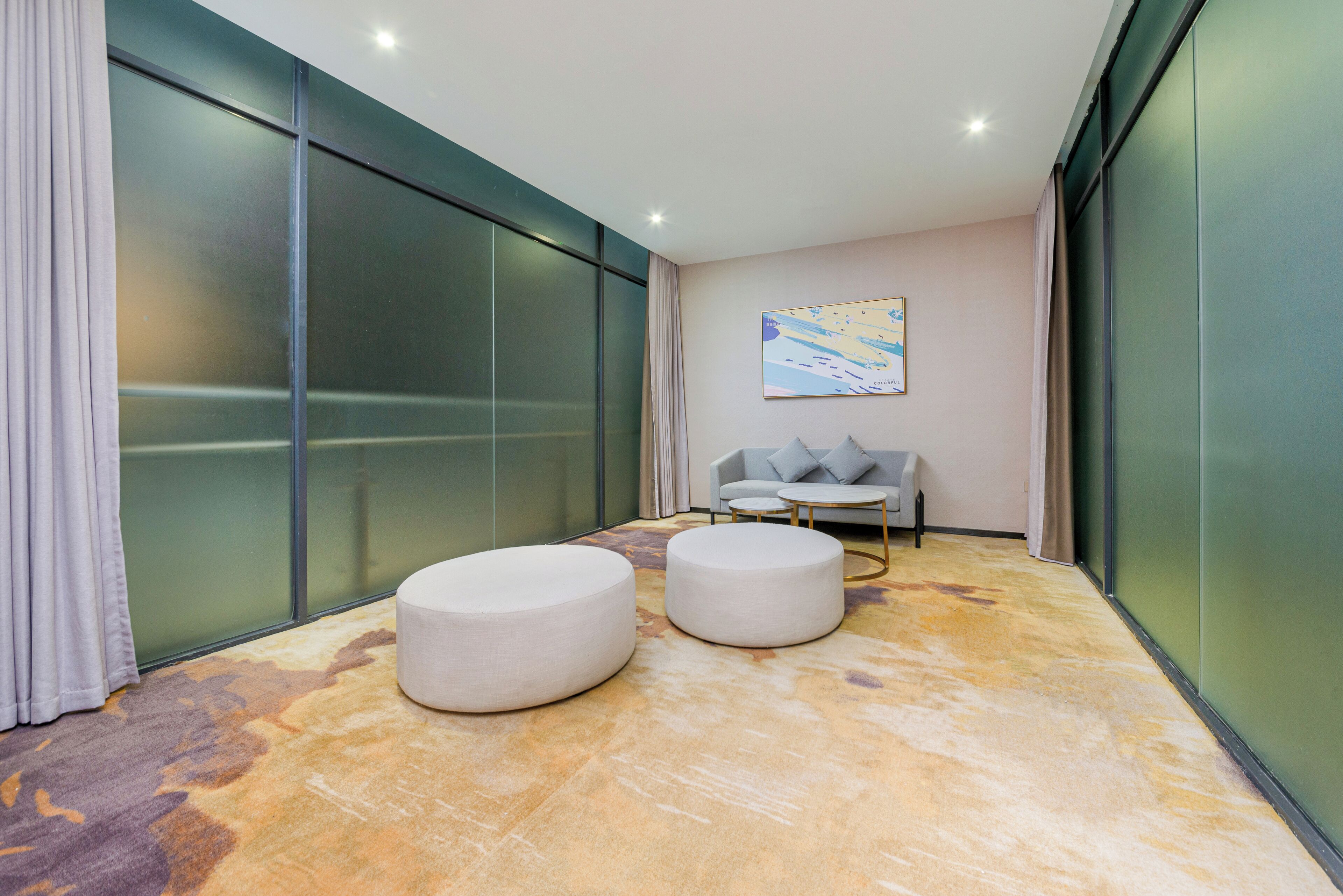 A modern interior with two round seating areas, a sofa, and a painting on the wall.