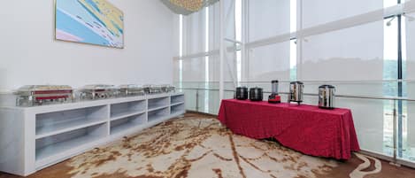 A room with a large window, a table with a red tablecloth, and a white console with shelves.
