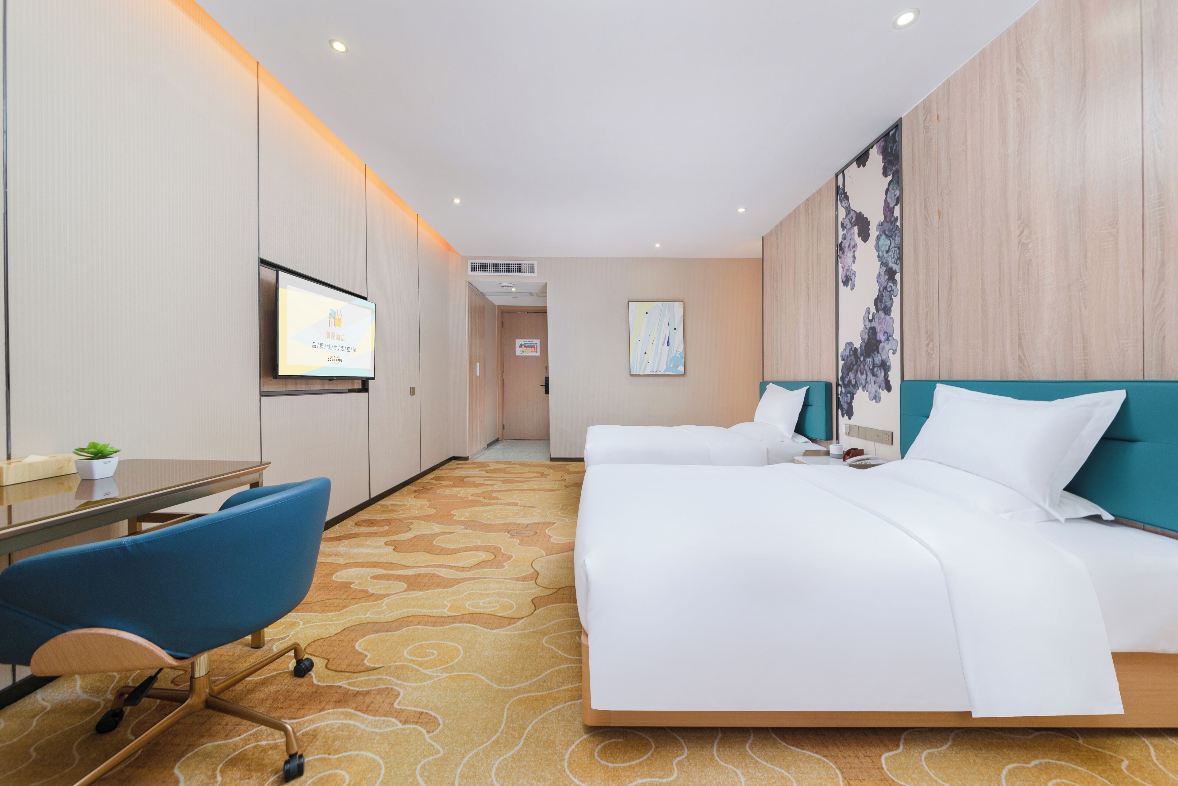 Ein Hotelzimmer mit einem großen Bett, einem Schreibtisch mit Stuhl, einem Fernseher und einer Pflanze.
