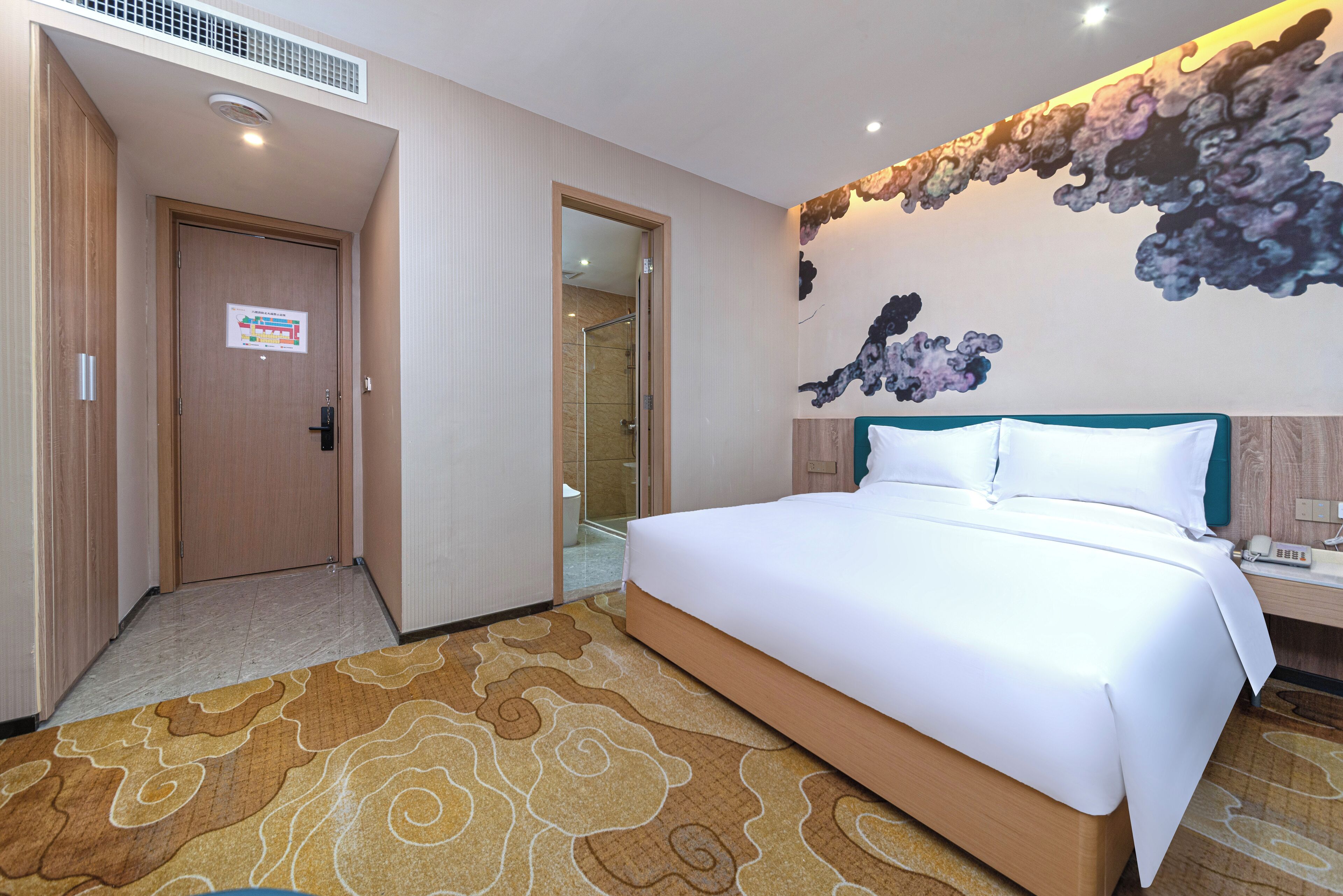 A hotel room with a large bed, a shower, and a wall with a cloud mural.