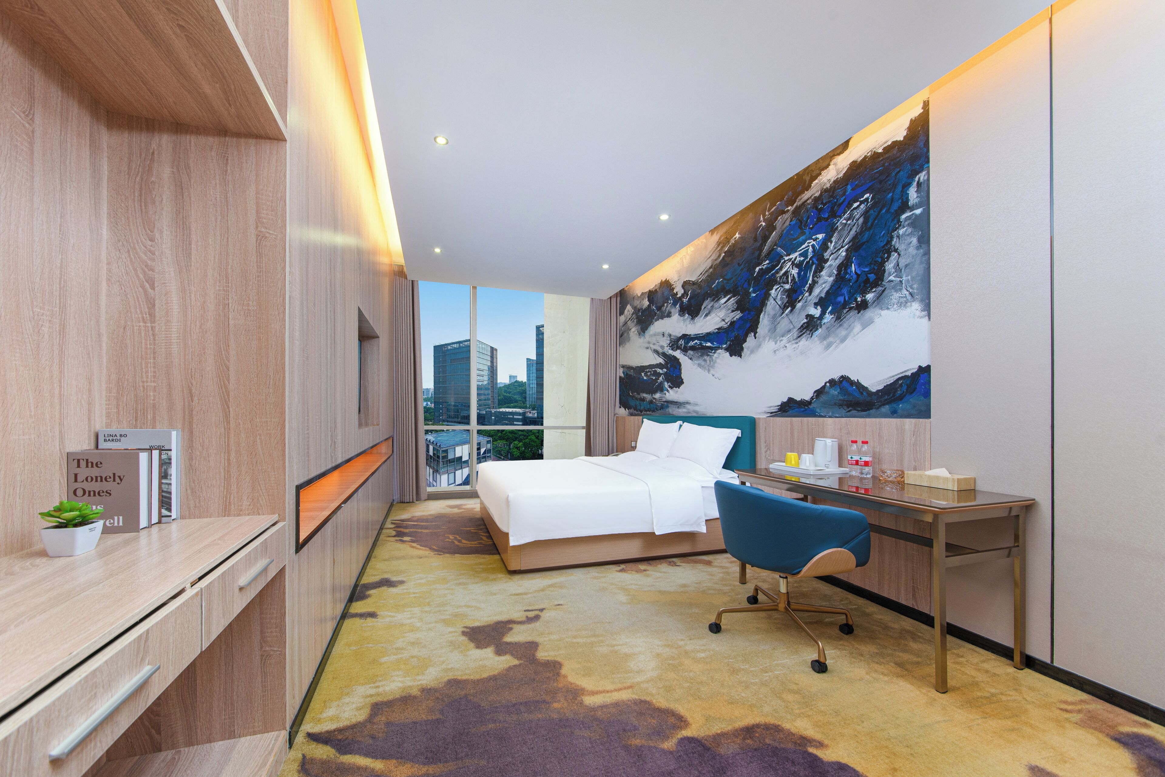A modern hotel room with a bed, desk, and a large window offering a city view.