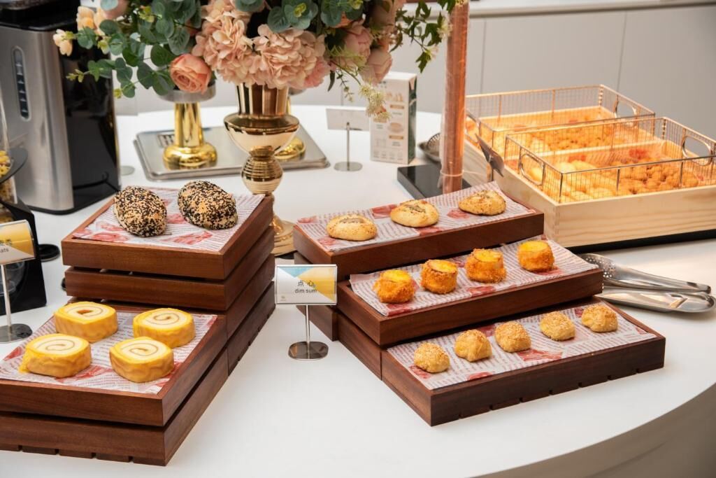 Una mesa de buffet con diversas opciones de panadería, incluyendo pasteles y panes, dispuestos sobre tablas de madera.