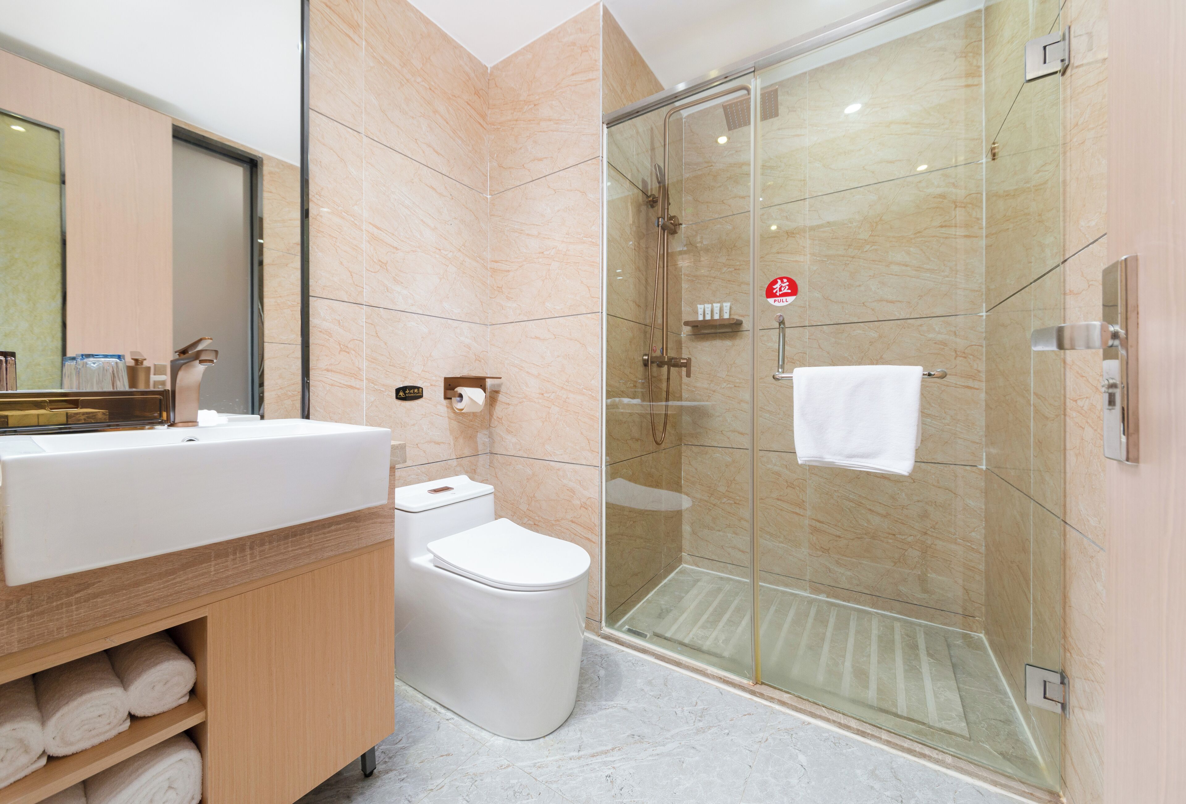 Un baño moderno con ducha envuelta en vidrio, un lavabo blanco y un inodoro.