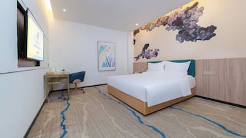 Una habitación de hotel moderna con una cama grande, un escritorio y un televisor montado en la pared.