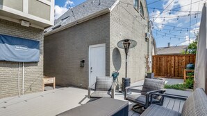 Eine Terrasse mit Gartenmöbeln, einem überdachten Sitzbereich und einer Ziegelwand.
