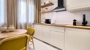 Una cocina moderna con armarios blancos, una encimera de madera y una silla amarilla. Hay dos jarrones en la mesa y una máquina de café en la encimera.