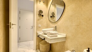 A modern bathroom with a white sink, a round mirror, and a toilet.