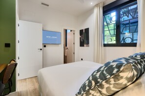 A hotel room with a bed, a TV mounted on the wall, a window with a view, and a door leading to another room. - Ground-floor one-bedroom with free parking (Sevilla)