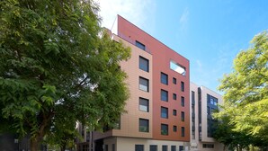 Um edifício de vários andares com design arquitetônico moderno, com uma combinação de janelas retangulares e quadradas.