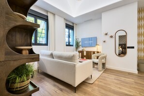 Uma sala de estar moderna com um sofá, uma mesa de centro, uma TV e um espelho.
