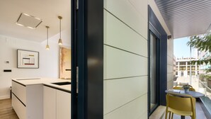 A modern kitchen with a white countertop, a sink, and pendant lighting. There is a dining area with a table and chairs outside the kitchen. - Viapol Homes 1.1 by Home at Homes (Sevilla)