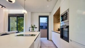 A modern kitchen with a central island, built-in appliances, and a view to the outside. - Viapol Homes 2.1 by Home at Homes (Sevilla)