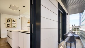 A modern kitchen with white cabinetry, a black countertop, and a dining area with a table and chairs. - Viapol Homes 3.1 by Home at Homes (Sevilla)