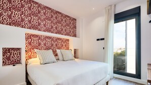 Ein Schlafzimmer mit einem großen Bett, strukturiertem Wandpapier und einer Schiebetür zum Balkon.