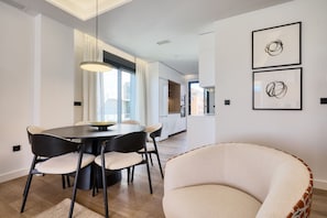 Un espace repas moderne avec une table ronde et des chaises, un luminaire suspendu et un canapé.