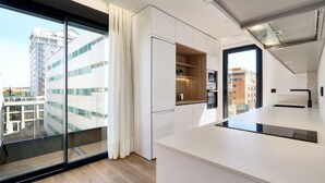 A modern kitchen with a large window, white cabinetry, and a view of a cityscape. - Viapol Homes 5.1 Ático by Home at Homes (Sevilla)