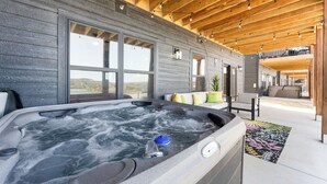 A hot tub in a modern, open-concept living area with large windows and a wooden ceiling.