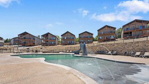 A pool area with a water feature, lounge chairs, and a row of multi-story buildings with balconies. - 2BR Retreat Near SDC w/ Hot Tub + Boat Slip (Branson)