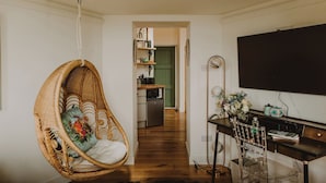 Een woonkamer met een rieten stoel, een bureau met een computer en een televisie.