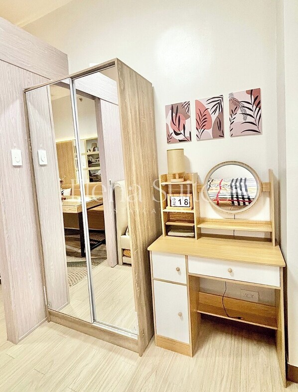 Un dormitorio con un escritorio de madera, un espejo y un armario.