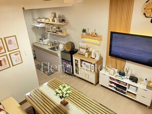 Eine moderne Küche mit Einbauofen, einer Kaffeestation und einem an der Wand befestigten Fernseher.