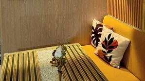 A modern living room with a wooden panel wall, a yellow sofa, and decorative wall art.