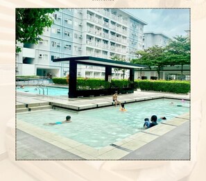 Zona de piscina con un edificio moderno al fondo.