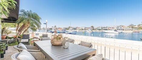 A patio with wicker furniture, a table, and a view of a marina with boats.