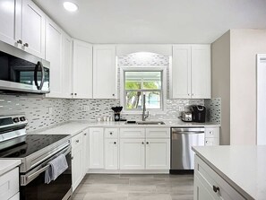 A modern kitchen with white cabinetry, stainless steel appliances, and a tiled backsplash.