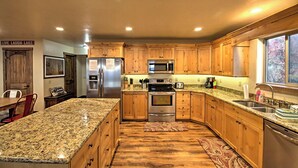 A kitchen with wooden cabinets, granite countertops, stainless steel appliances, and a window providing natural light.