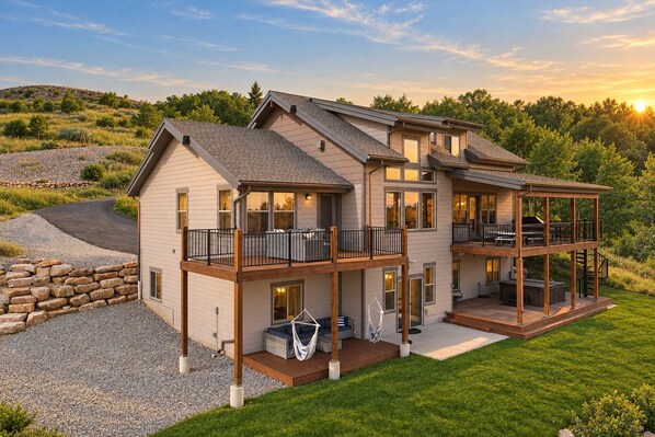 A two-story house with a deck, a covered porch, and a stone retaining wall.