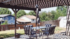 Una terrazza esterna con una pergola, un tavolo con sedie e una lampada a sospensione.