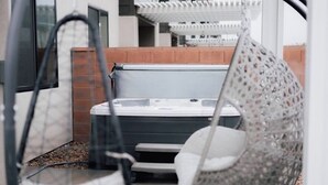 Een bubbelbad in een overdekte buitenruimte met een pergola erboven.