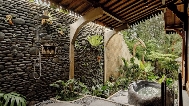A stone-walled spa area with a hot tub, shower, and various tropical plants. - Hidden Saren Villa Ubud (Ubud)