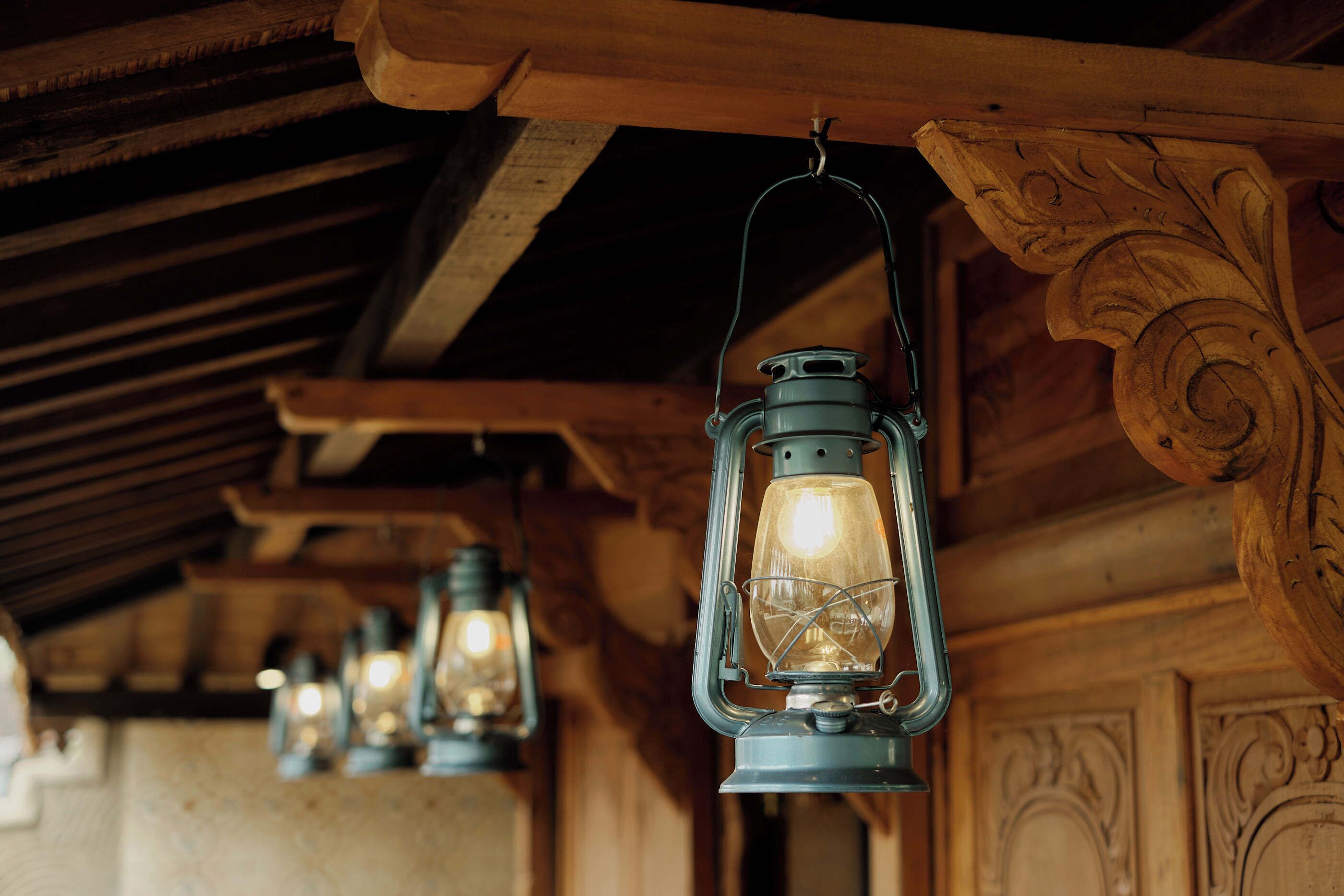 A series of hanging lanterns with a rustic wooden ceiling and carved details.