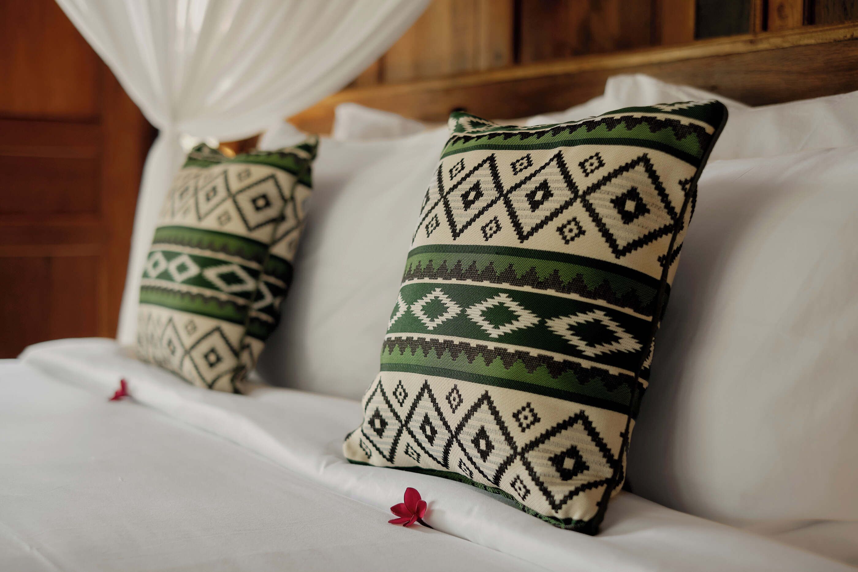 Dos almohadas con un diseño geométrico sobre una cama con sábanas blancas.