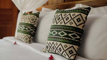 Dos almohadas con un diseño geométrico sobre una cama con sábanas blancas.