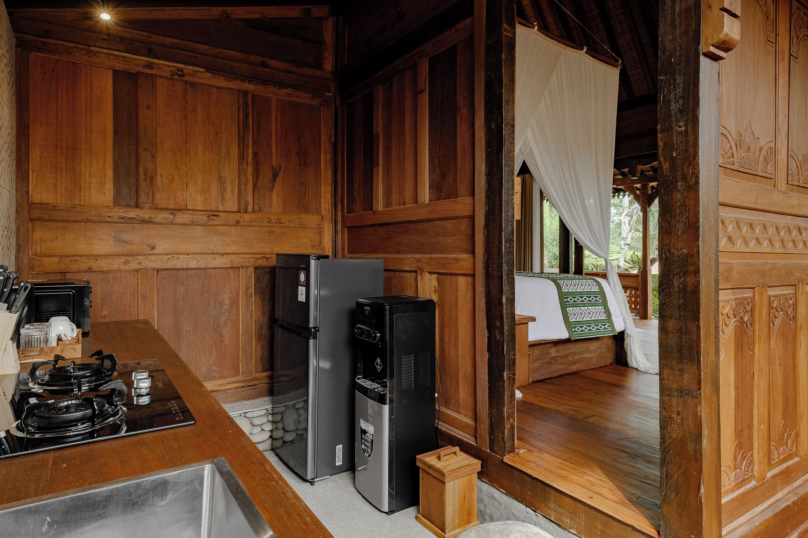Un interior de madera con una zona de cocina, que incluye estufa, refrigerador y lavamanos.