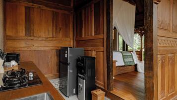 Un interior de madera con una zona de cocina, que incluye estufa, refrigerador y lavamanos.