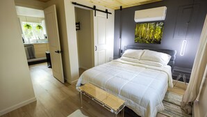 A bedroom with a bed, a bench, and a view of the kitchen and bathroom. - Deer Trails Retreat•Games•Fire Pit•Near Kalahari•Pocono•Camelback (Pocono Summit)