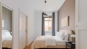 A bedroom with a bed, bedside table, and a window with curtains.