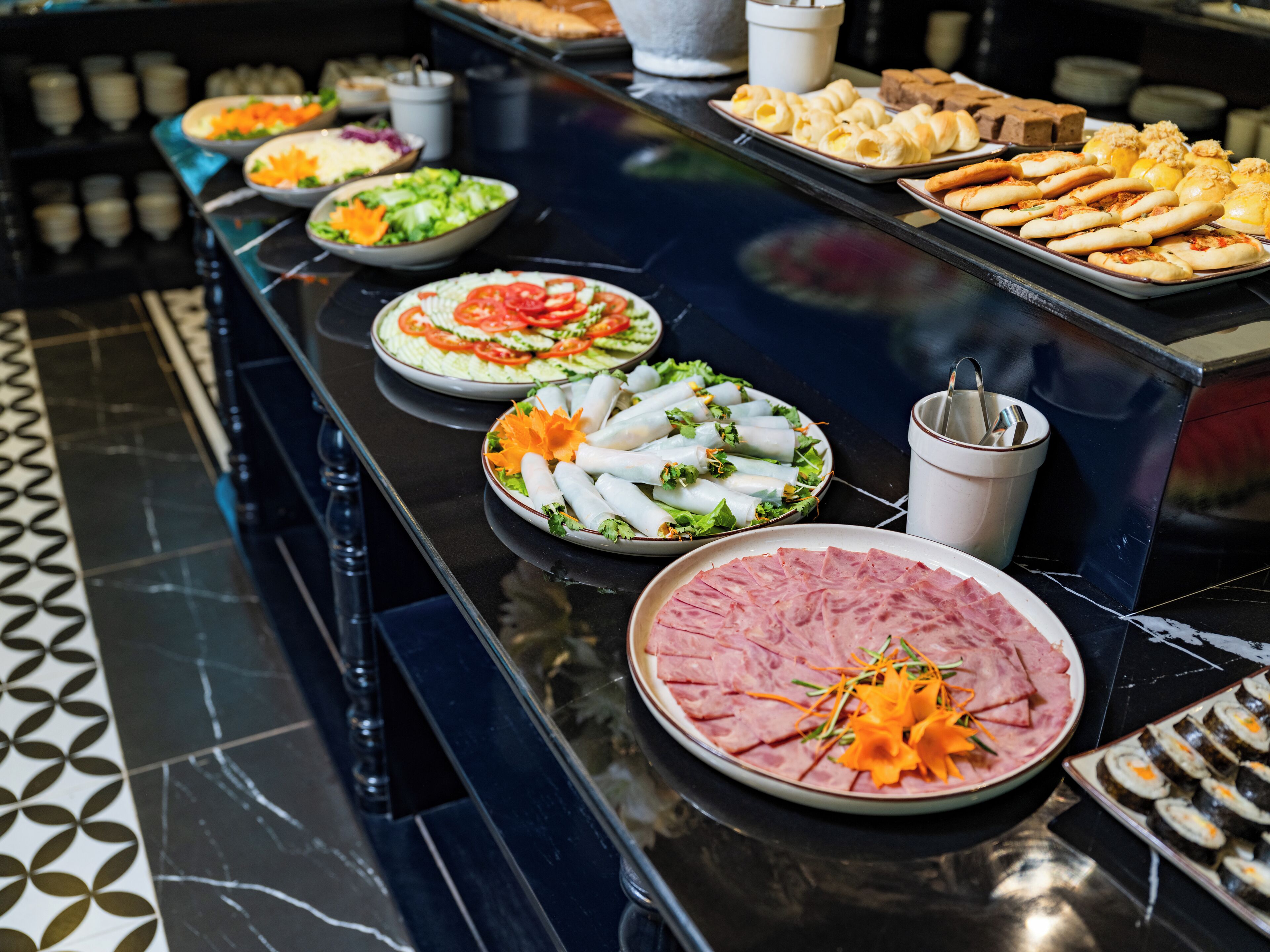 A buffet table with various dishes including salads, sandwiches, and sliced meats.