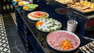 A buffet table with various dishes including salads, sandwiches, and sliced meats.