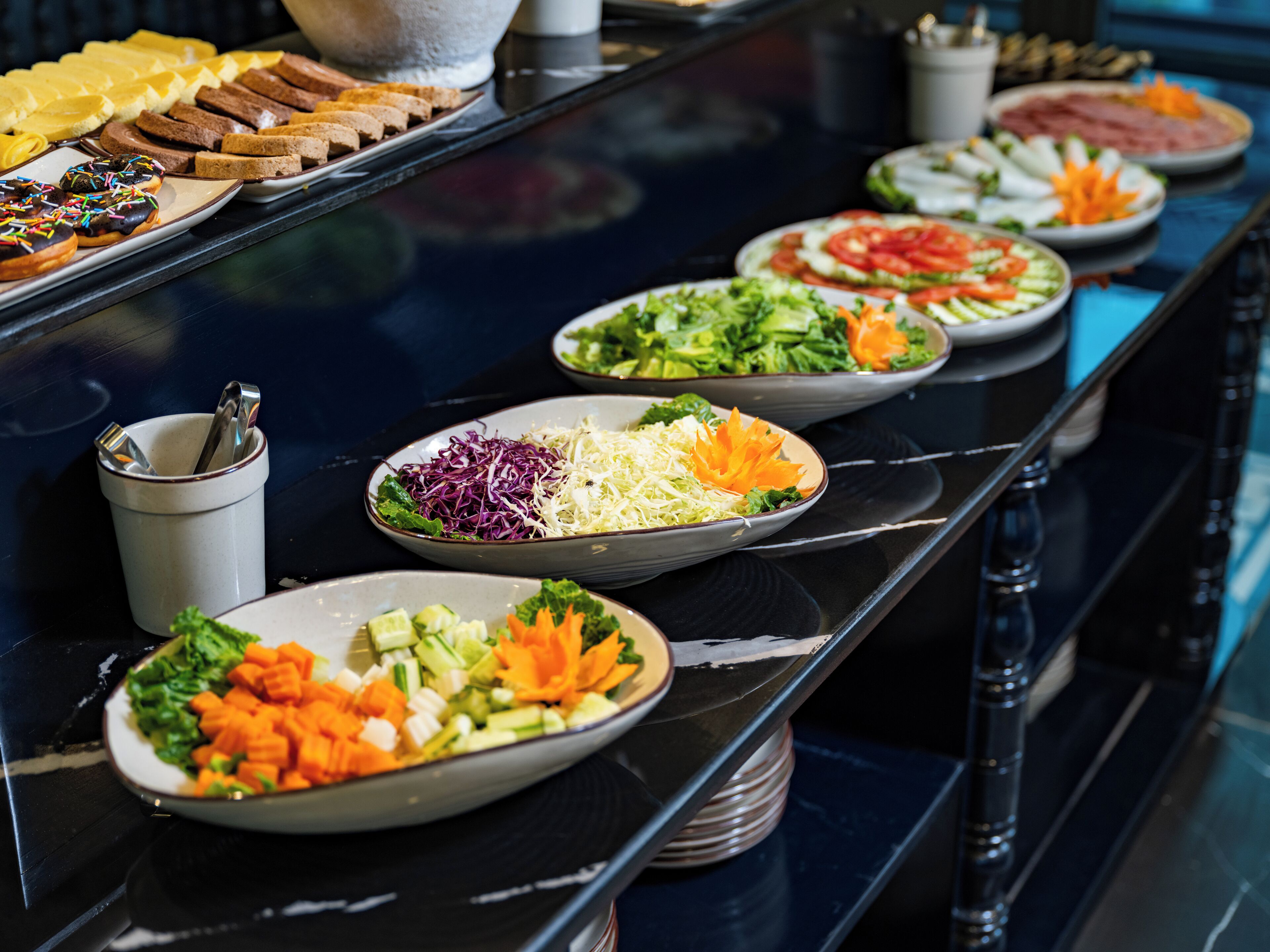 Een buffet met diverse gerechten, zoals salades, groenten en brood.