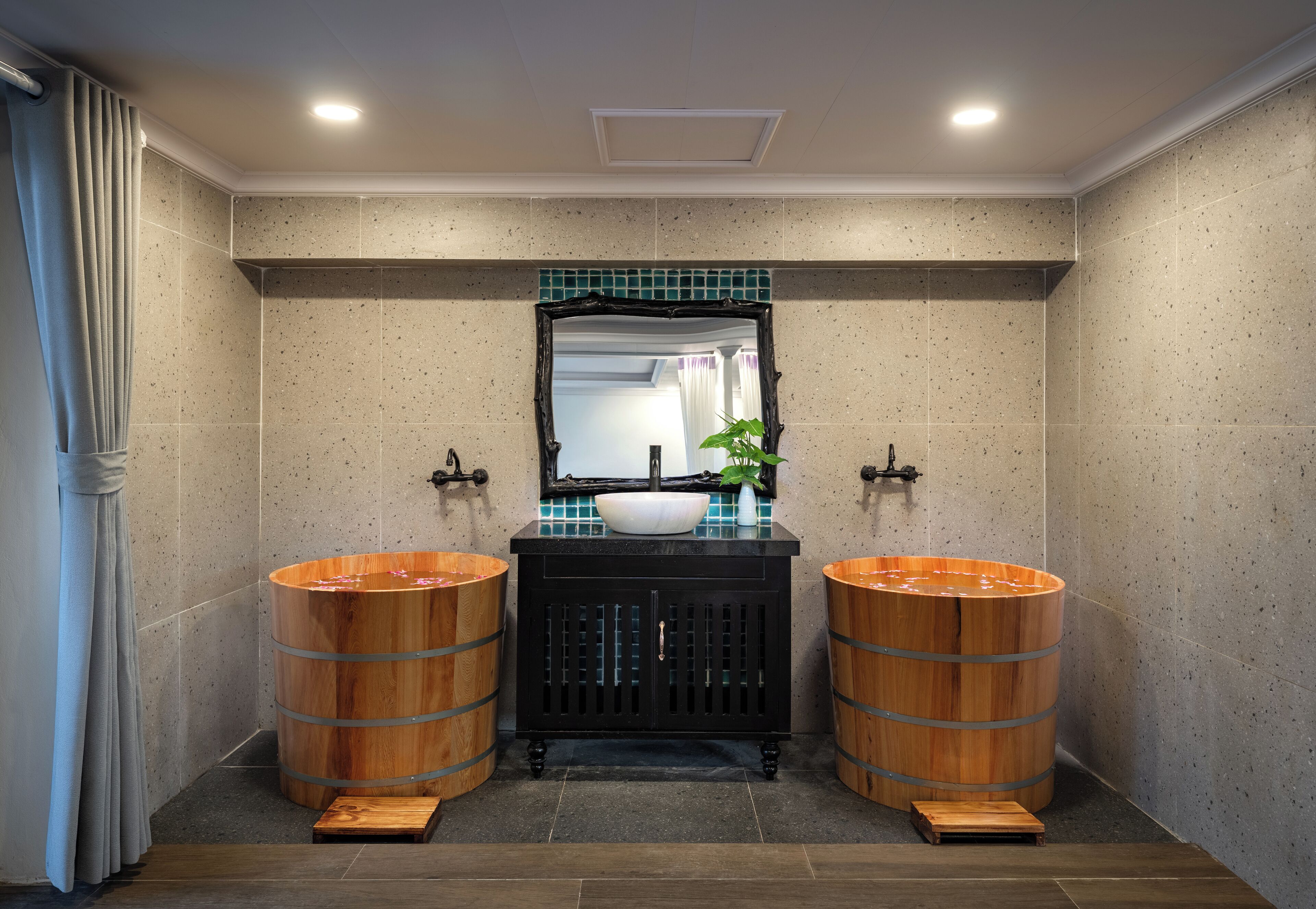 Une salle de bain avec deux tonneaux en bois, un lavabo et un miroir.