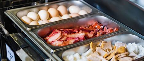 Un bufé con diversas opciones de comida, como huevos, tocino y pollo.