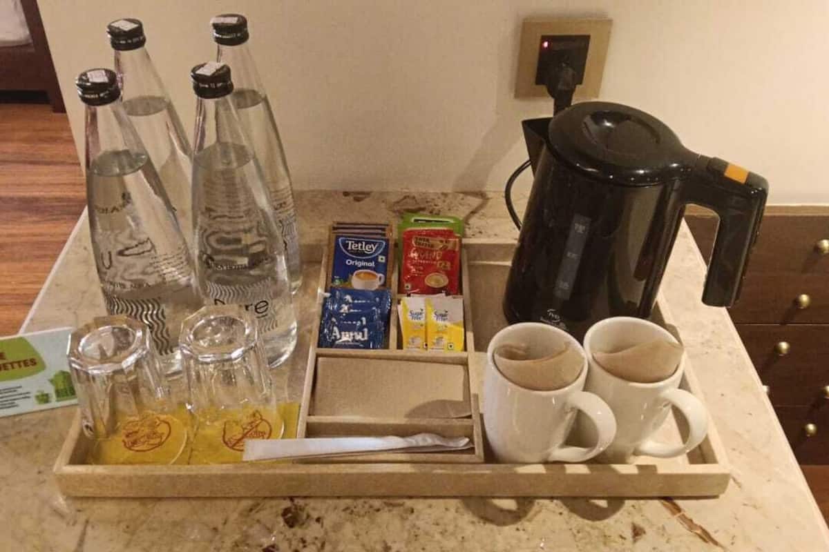 A kitchen counter with a tray containing tea kettles, coffee mugs, and tea bags.