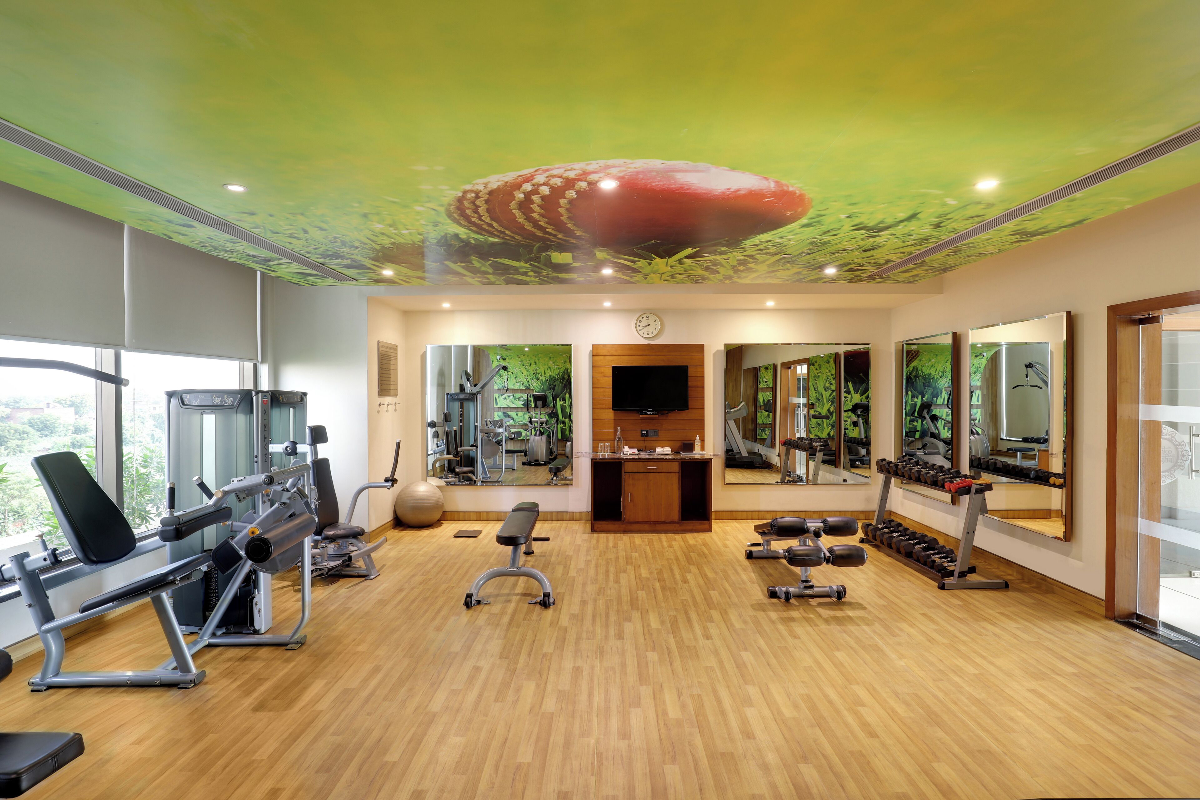 A gym with exercise equipment, a bench, and a television.